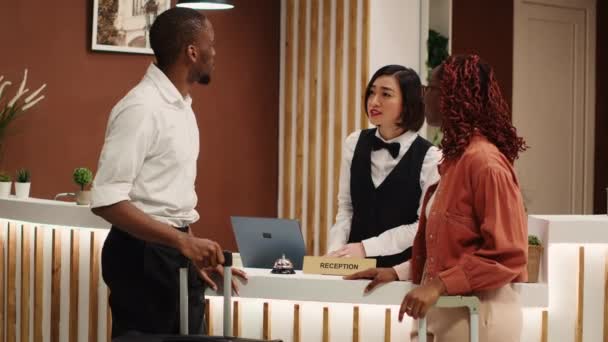 Helpful Asian Receptionist Presenting Holiday Package Options African American Couple — Stock Video