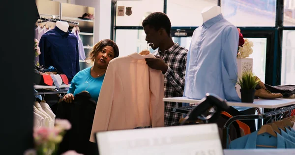 アフリカ系アメリカ人のカップルは流行の商品を見て それを購入する前に服生地をチェックする お店のお客様ショッピングのためのファッショナブルな衣装やスタイリッシュなアクセサリーで現代ブティック — ストック写真