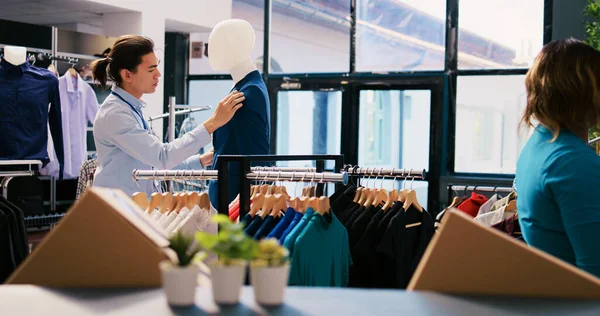 アジアのマネージャーは モダンなブティックでファッショナブルな服やスタイリッシュなアクセサリーを配置し 青いスーツボタンを閉じます 衣料品店のビジュアルで働く陽気な従業員 ファッションコンセプト — ストック写真