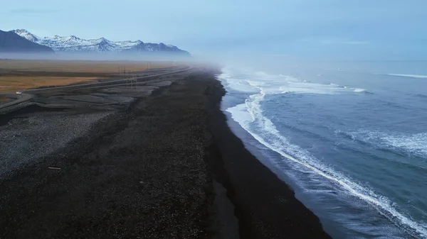 アイスランドの黒砂のビーチドローン 大西洋岸に波がクラッシュして美しい海岸線を撮影しました ビーチで雪の山と黒砂 風光明媚なルートと北欧の風景 スローモーション — ストック写真