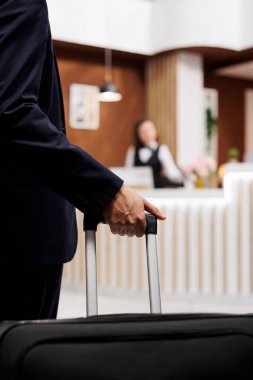 Otel misafiri bavulla resepsiyona giriyor, önemli iş toplantılarına katılmak için yurtdışına gidiyor. Girişimci kayıt için resepsiyona yaklaşıyor, konaklama ayarlanıyor. Kapat..