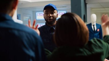 Müşteriler, Kara Cuma alışverişi sırasında giyim mağazasında ilk olmak için birbirlerini itiyorlar. Afro-Amerikan muhafızlar alışveriş merkezinin içindeki saldırgan kalabalığı engelliyor. El kamerasıyla..