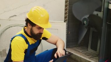 Yeni havalandırma vantilatörünü aramak için tablet kullanan eğitimli mühendis, müşteri kontrolleri sırasında açık hava havalandırma arızalı havalandırma bölümünü buldu.
