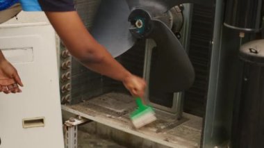Çalışkan tamirci, HVC sisteminin iç kısımlarında biriken döküntüleri temizliyor. Yetenekli bir uzman, soğutma kapasitesinin azaltılmasını önlemek için iç kısımlardan toprak tabakası oluşturdu.