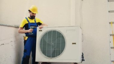 Uzman telci, çalışan klima üzerinde çalışmaya başlıyor. Yoğunlaştırıcı bobin panelini ayırmak için el matkabı kullanıyor. Hatalı kabloları kontrol etmek için yetkili mekanik sökücü hvac sistemi