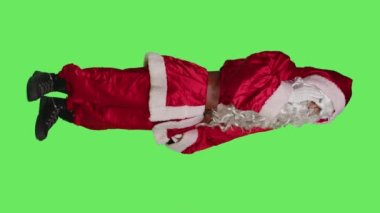 Noel Baba 'nın dikey görüntüsü, kış tatillerinde baş ağrısı çekerken, yeşil ekranda geleneksel bir kostüm giyerken. Noel Baba migrenden muzdarip.