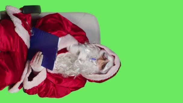 Вертикальное Видео Фронт Вью Санта Клауса Человека Делающего Заметки Планшете — стоковое видео