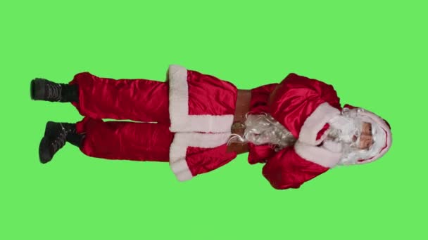 垂直方向のビデオカメラで聖人ニック雹誰かのフロントビューでは 人々が来て 彼に参加を求めている 父クリスマスの具現化の衣装を着て人を呼び出すに同行し 全身の緑の画面 — ストック動画