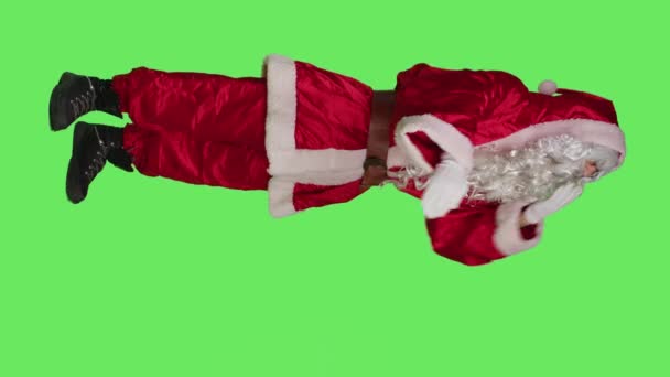 垂直ビデオロマンチックなサンタクラスのサイドビューは 緑の背景に空気のキスを送信します カメラで浮気と甘い演技 12月の休日を広めるロマンスジェスチャーを示す父のクリスマス — ストック動画