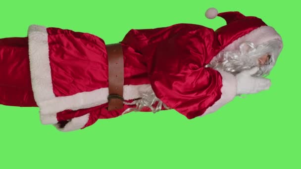 垂直ビデオクリスマスの前夜のお祝いに疲れを感じ 隔離された緑の背景の上に輝く過労したサンタクラスのキャラクターのサイドビュー 眠い伝統を描いた若い人 — ストック動画