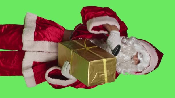 垂直ビデオパッケージ内のプレゼントのためのスキャナを使用して 緑の背景に聖人ニック文字スキャンギフトボックスのフロントビュー サンタは冬にクリスマスの精神を広める準備をする — ストック動画
