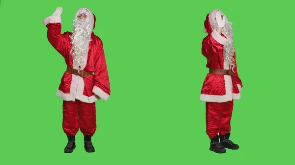 快乐的性格在镜头前挥手致意 问候他人 传播圣诞节的积极因素 圣诞老人穿着带有帽子和白胡子的标志性红色服装 一边说 — 图库照片