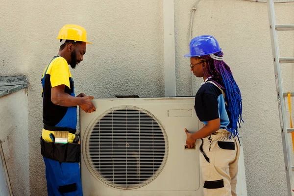 非洲裔美国工程师同事在用完制冷剂和更换管道后 打开已停用的生锈的空调机 代之以新的外冷凝器性能 — 图库照片