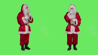 Noel Baba kırmızı şenlikli kış kostümü içinde bir fincan sıcak çikolata içer ve yeşil ekran arka planında kahve içmenin tadını çıkarır. Noel Baba mevsimlik içeceklerle.