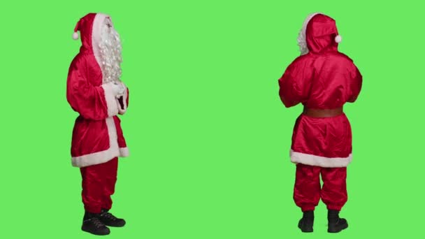 カメラで笑う聖ニックのキャラクター ホホと言って 冬休みの間にクリスマス精神を広める 赤い衣装と帽子でサンタの格好をした若い男 フルボディの緑の画面 — ストック動画