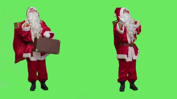 サンタはスーツケースとプレゼント付きのハイキングをして クリスマスの前夜の精神と積極性を広げています プレゼントやブリーフケースを持って聖人ニックのように振る舞う人はおもちゃを配達する — ストック動画