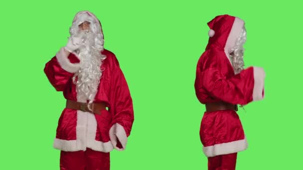 クリスマスはスタジオにいないと言い 緑の背景に立っているいたずらな子供たちに失望しています お祝いのサンタクラスのスーツを着て 不満と不満を行動する人 — ストック動画