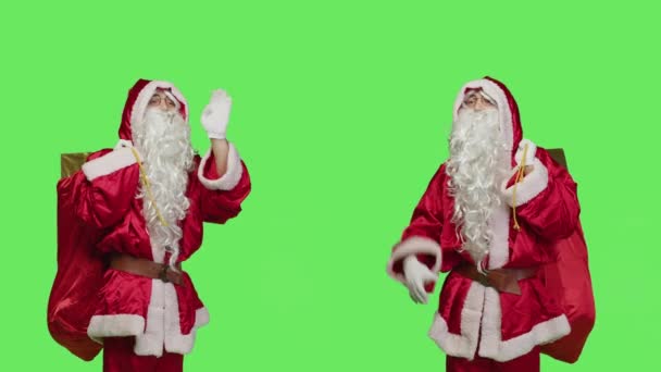 スタジオでこんにちはや別れを振って楽しいサンタは クリスマス休暇の精神を広める幸せを感じています 男聖人ニックとともに袋にフルプレゼントボックス祝う伝統的な12月のイベント — ストック動画