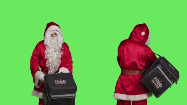 緑の背景に赤いスーツでお祝いの季節の文字を描いた 熱バックパックでピザを提供する衣装の男 12月の休日のお祝い髭を生やした配達人 — ストック動画