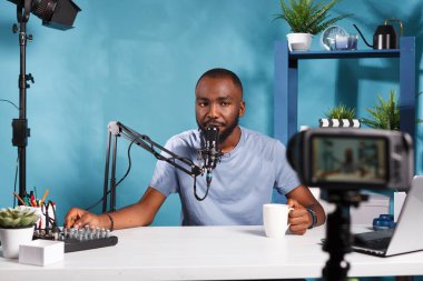 Ses kontrol konsolu kullanan ve profesyonel kamerayla video kaydeden Afrikalı Amerikalı bir vlogger. Stüdyoda sosyal medya kanalı için dijital içerik oluşturan blogger