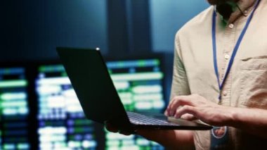 Computer scientist using laptop to check data center security to make sure virus protection software is up to date and hackers trying to penetrate systems are denied, close up