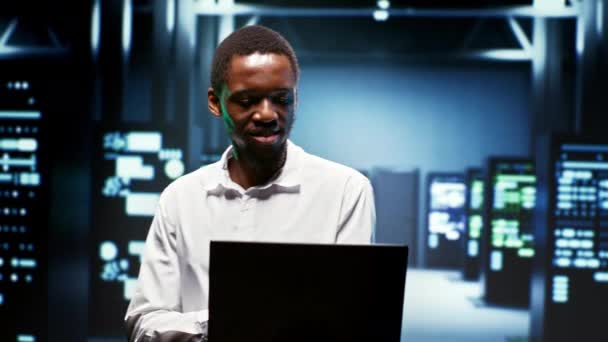 快乐的非洲裔美国员工使用笔记本电脑查看服务器机柜组件的能源消耗 确保数据中心电子温度传感器正常工作的工人 — 图库视频影像