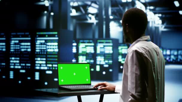 スーパーコンピュータを検査するために緑色の画面のラップトップを使用してスーパーコンピュータを監視します 電力使用を促進するAiアプリケーションによるデータセンターハードウェアの負担を防止する専門家 — ストック動画