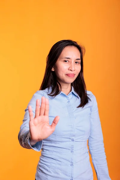 严肃的菲利皮诺女人举起手掌 在工作室黄色背景上做停止手势的广告 表示否认和拒绝 展示拒绝姿态 做拒绝标志的模型 — 图库照片