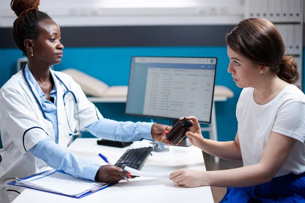 stock image General practitioner doctor offering clinical consultation to patient. medicine. Healthcare specialist during checkup prescribing pill bottle medicine to woman in modern clinic