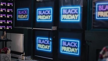 Store entrance decorated on black friday with neon signs, inside shopping center. Clothing shop interior with fashion items on racks, waiting for customers to buy products on shopping day.