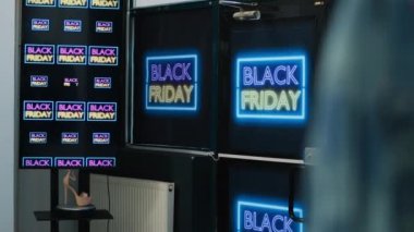 Siyah cuma tabelası olan giyim mağazasının girişi, perakende mağazasının ön kapısı. Raflarda asılı moda eşyalarıyla alışveriş merkezi, promosyonlar ve indirimli afişlerle süslenmiş yer..