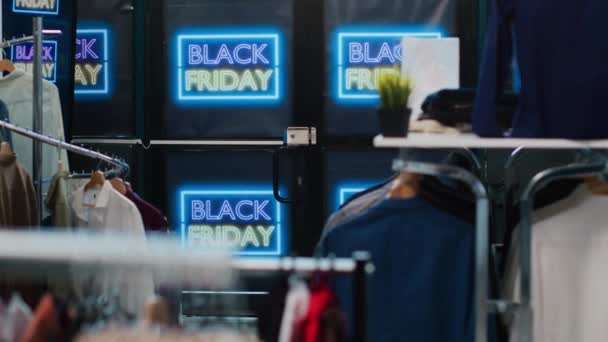 黒の金曜日の小売店は ショッピングセンターで11月の季節の販売を提供しています ファッションブティックの小さな価格で服 顧客を引き付けるための特別なプロモーションを持つネオンバナー — ストック動画
