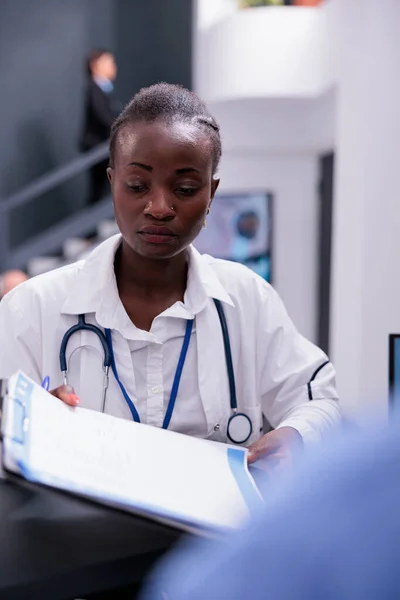 アフリカ系アメリカ人医師は 病院の待合室での薬物治療で一緒に働く患者の症状を議論するのを助けるために医学報告を与える 医療サービスとコンセプト — ストック写真
