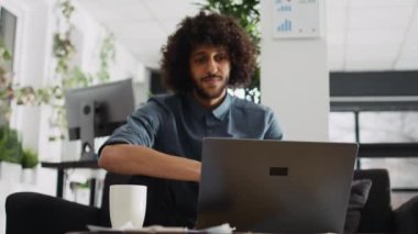 Startup CEO 'su şirket çözümünü açıklamak için çevrimiçi video konferans görüşmesini kullanarak video bağlantısı ile iş toplantısına katılıyor. Şirketin girişimcisi açık ofiste. Üçayak atışı.