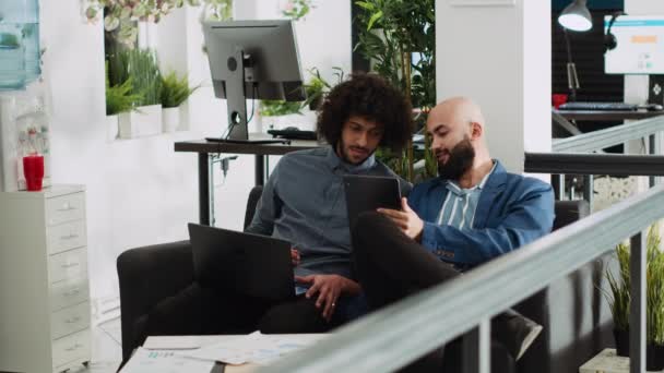 Два Співробітники Порівнюють Нотатки Офісі Переглядаючи Дані Онлайн Компаній Ноутбуці — стокове відео