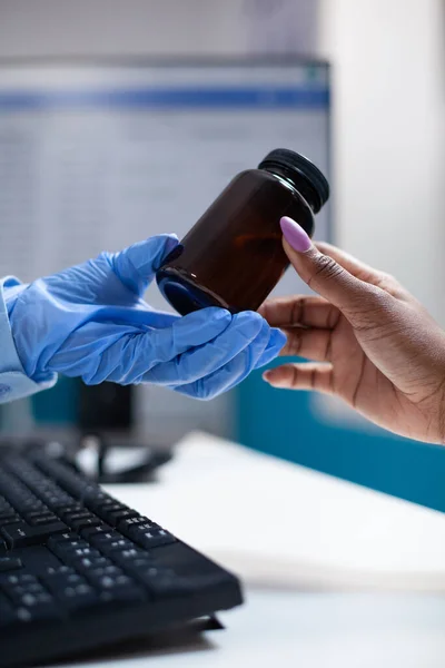 의사가 예약중에 환자에게 약병을 제공하고 병원내에 의약품을 처방하는 보호하는 장갑을 — 스톡 사진