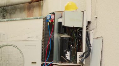 Defective outside air conditioner system with protection cover removed in need of fixing, with broken electric internal bits. External HVAC system not functional anymore, ready to be refurbished