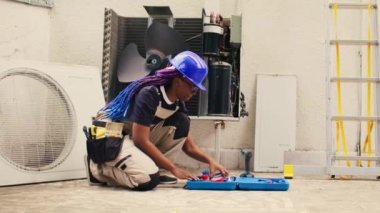 Knowleadgeable engineer preparing for annual condenser maintenance. Efficient technician unpacking toolset box with professional gear needed to mend damaged air conditioner internal parts