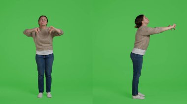 Kadın model kamerada olumsuz işaretler gösteriyor. Onaylamıyor ve kötü bir sembol çiziyor. Kendine güveni tam bir kadın tüm yeşil ekran üzerinde hoşnutsuzluk jesti ile anlaşmazlık ifade.