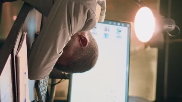 垂直视频非洲裔美国计算机操作员在办公室工作通宵 睡在桌椅上 累了的员工在工作时打盹 一个人在未完成任务的工作空间里 — 图库视频影像