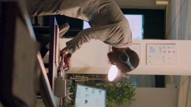 İşyerinde müzikle eğlenirken dans eden dikey video çalışanı, bilgisayarla çalışmaktan yoruldu. Enfes dans figürleri sergileyen bir iş adamı ofiste dönüp iş arkadaşını güldürüyor.
