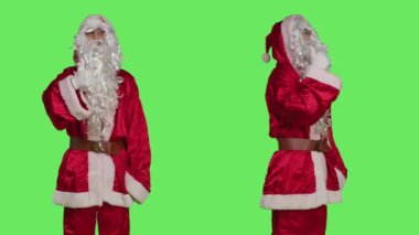 Noel Baba, başparmak işareti yapıyor. Şapkalı, beyaz sakallı, Noel Baba 'yı canlandırıyor. Kırmızı elbiseli kendine güvenen adam yeşil ekran arka planında onay jesti gibi görünüyor..