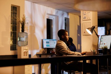 Girişimci, mali büyüme raporunda çalışan şirket istatistiklerini gece geç saatlerde yeni açılan ofiste analiz ediyor. Afrika kökenli Amerikalı yönetici ticari karı artırmak için pazarlama stratejisi planlıyor