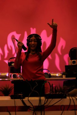 Neşeli Asyalı sanatçı, profesyonel ses ekipmanlarıyla gece kulübünde performans sergiliyor. Partiden ve elektronik müziği karıştırmaktan hoşlanıyor. Performans sanatçısı turntable 'larda melodi üretmek için sesler çalıyor