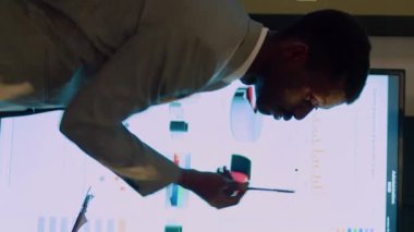 Modern ofiste gece vardiyasında şirket gelirleri istatistikleri üzerinde çalışan dikey video ekibi çalışanları. Önemli proje görevlerini çözen meslektaşlar, dijital ekranda grafikleri kontrol edenler