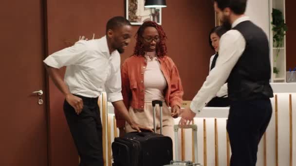 택시로 수하물을 운반하는 유용한 직원을 행복한 쾌활한 아프리카계 미국인 관광객은 — 비디오