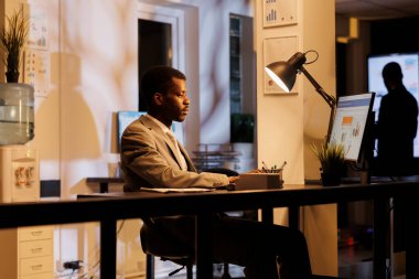 Girişimci daktilo yönetimi stratejisi şirket istatistiklerini analiz ediyor, başlangıç ofisinde fazla mesai yapıyor. İdari Müdür, pazarlama projesi ve iş konsepti hakkında fikir alışverişinde bulunuyor.