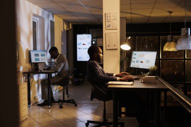 Afrikalı Amerikalı iş adamı pazarlama projesinde fazla mesai yapıyor, bilgisayardaki grafikleri analiz ediyor. Finans stratejisi planlayan yönetici şirket büyüme raporu. İş konsepti