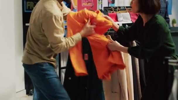 在黑色星期五的促销活动中 人们疯狂购物 为打折的衣服争论不休 愤怒的顾客拉着商品 沉迷于促销清关物品 — 图库视频影像