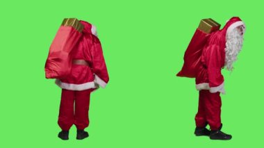 Noel Baba, Noel Baba kostümü içinde hediyeler taşıyor. Kırmızı bir çuvalla. Stüdyoda bayram ruhu yayıyor. Yeşil ekran arkaplanına bakan hediyelerle dolu Aziz Nick 'in vücut bulmuş hali.